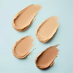 three full coverage conceals, all shades light and medium - dark on a blue surface