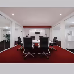 a meeting room with modern white tables and black chairs