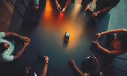 people sit around and look at cell phones in a circle