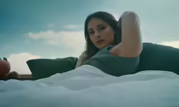 a beautiful young woman laying on a bed with her hands behind her head