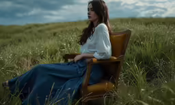 woman sitting in chair on grassy field on cloudy day