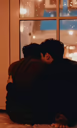 a couple are sitting on a bed and kissing by a window
