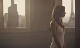 a woman standing in front of windows and looking into the distance