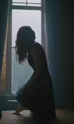 a young woman sits in front of an open window