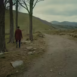 a man walks away from the camera down a dirt path