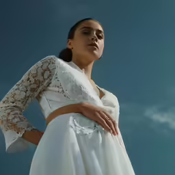 a woman in a white dress stands on the edge of a bridge and poses for the camera