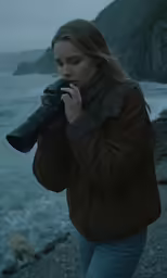 the woman is on the side of the mountain looking at the water