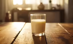 a glass full of milk sits on a table