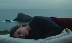 a young woman laying on the edge of the ocean