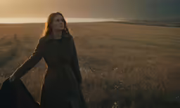 a woman is standing in the grass with her hands on her hips
