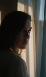 a woman is staring out the window at the outside