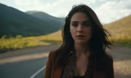 a beautiful young woman standing on the side of a road