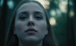 a woman is staring while standing in a forest