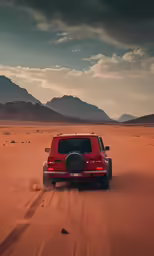 a red car is driving through the desert with mountains in the background