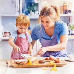 a mother and her toddler preparing food on a wooden board