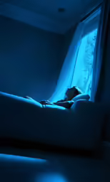 a boy lying in a light filled room on a couch