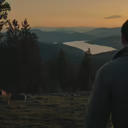 a man is looking down at a lake