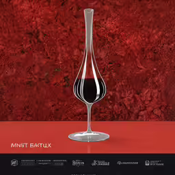 a single wine glass sitting on top of a table,red wine is in a tall, elegant crystal glass
