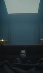 a woman lying on a couch under a skylight