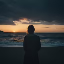 someone is standing on the beach in front of the water