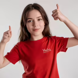 the woman poses in red t - shirt holding a thumb up