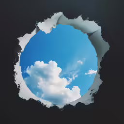 a picture of a blue cloudy sky seen through a torn paper hole
