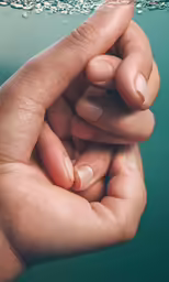 two hands hold each other with a bead above them