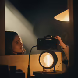 a woman holding a camera and a light sitting in front of her