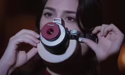 a girl looking through a camera lens with a red lens