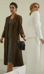 two women standing next to each other near a camera