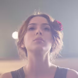 a girl is sitting down with her head resting on a small flower
