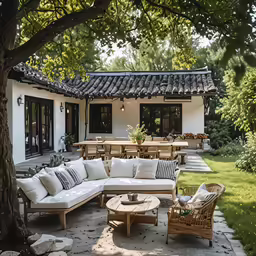 a patio area with an outdoor seating set and a large tree