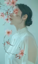 an asian woman looks to her side at pink flowers