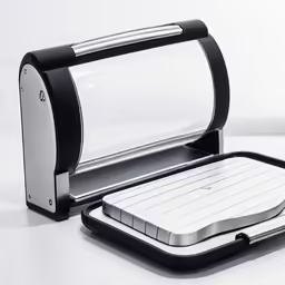 an open black and silver plastic dish with food preparation equipment