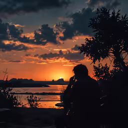 a person sits on a bench as the sun sets