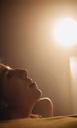 a close up of a person laying in bed under a light