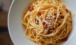 a white bowl filled with spaghetti and sauce