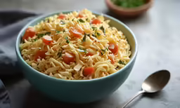 a pasta salad with tomatoes, cheese and herbs in a bowl