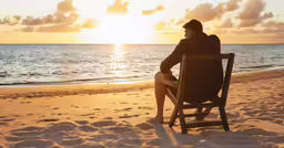 a person sitting on a beach next to a chair