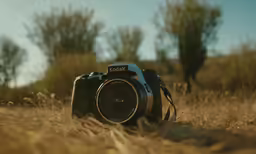 a canon camera in the middle of some tall grass