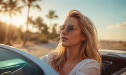 a woman sitting in the driver seat of a car in front of palm trees