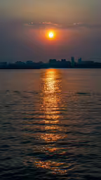 a body of water with the sun going down,a sunrise view from the back of a ferry boat