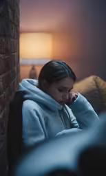 a girl sitting alone and staring intently in her blue sweatshirt