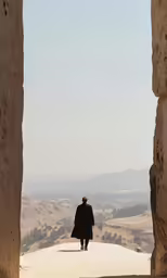 a person in long black coat walking among big rocks
