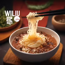 a bowl of soup with noodles and beans is being served with chopsticks