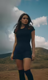a beautiful young woman in a short dress standing on a field