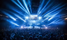 an audience in front of a stage filled with bright lights