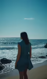 the back view of a woman standing in the sand