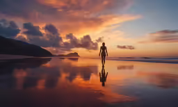a person walking down a beach at sunset