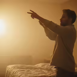 a man in tan shirt pointing towards sunlight